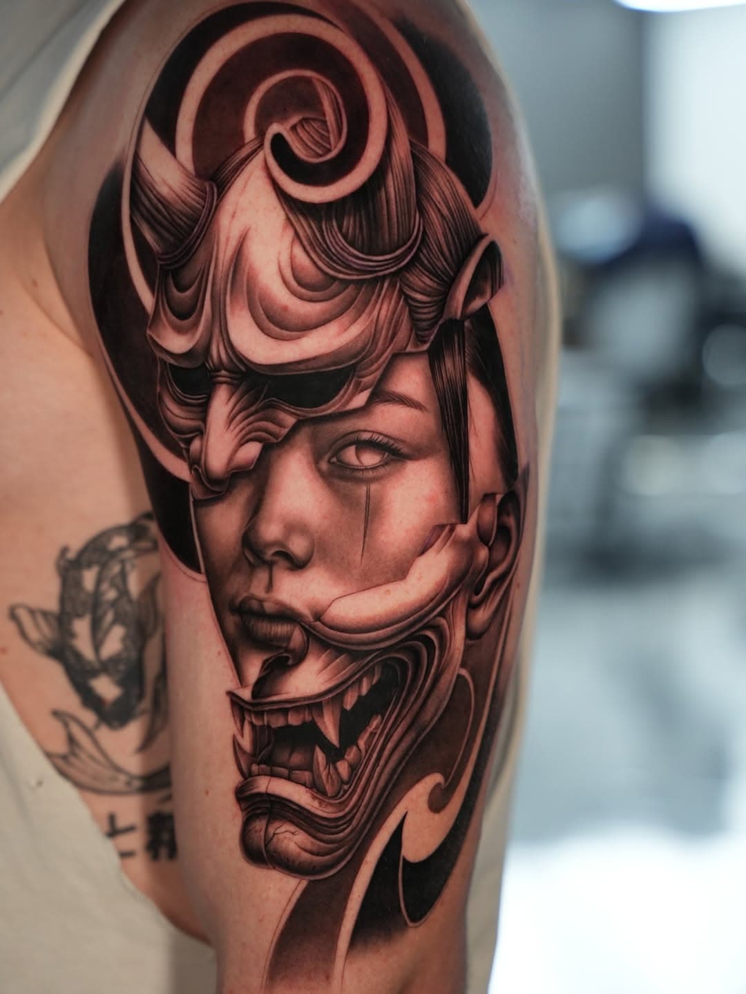 Black and grey Japanese hannya mask merged with woman portrait tattoo on arm by Ink Theory